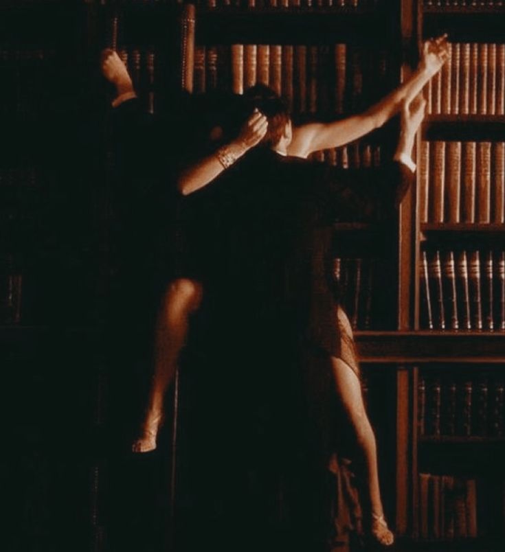 a man and woman standing next to each other in front of a bookshelf