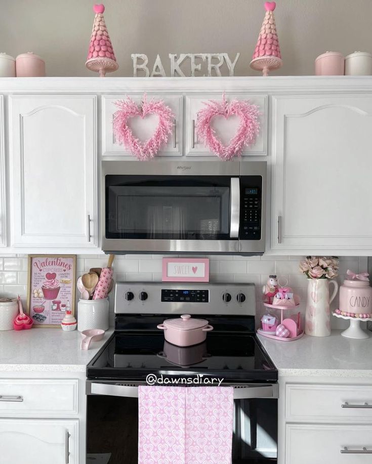 a kitchen with white cabinets and pink decorations on the wall above the stove top oven