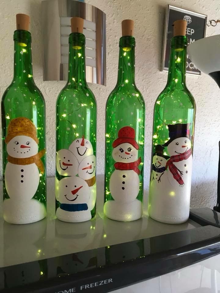 three wine bottles with snowmen painted on them, one is green and the other is white