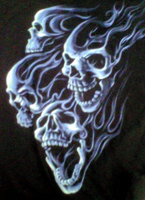 three skulls with flames on their faces glow in the dark