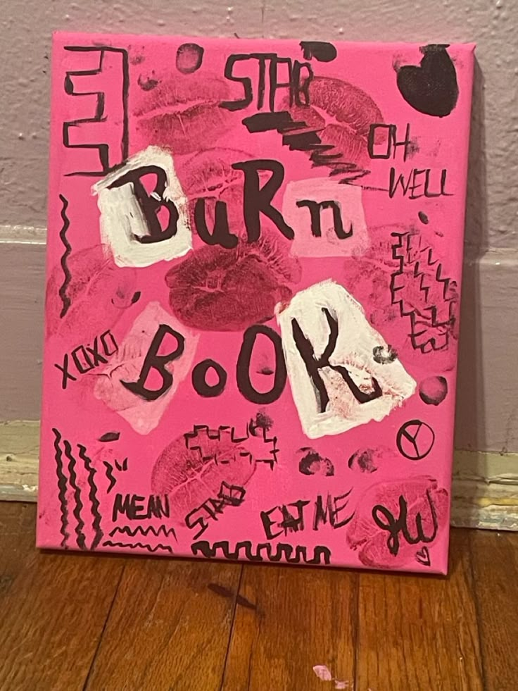 a pink painting with black writing on it sitting on top of a hard wood floor