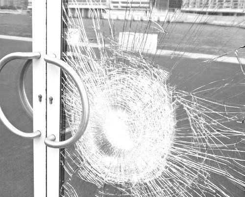 a broken glass door on the side of a building with an open handle in black and white