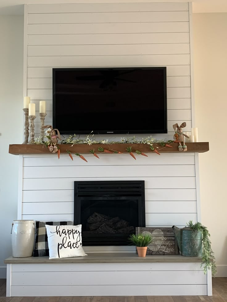 a flat screen tv mounted above a fireplace with candles on the mantel below it