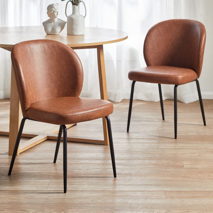 two brown chairs sitting next to each other on top of a wooden floor