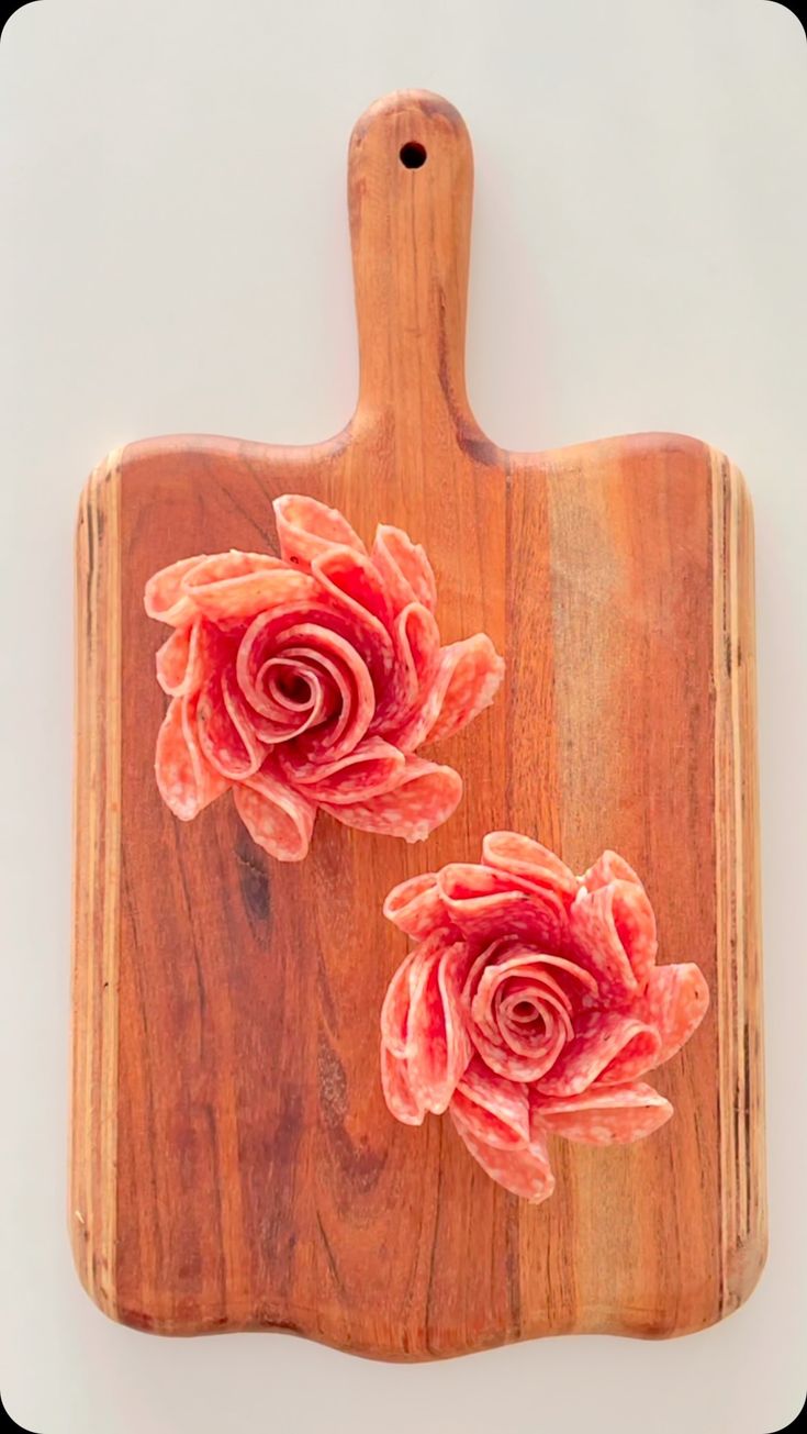 a cutting board with two pink flowers on the top and one red flower on the bottom