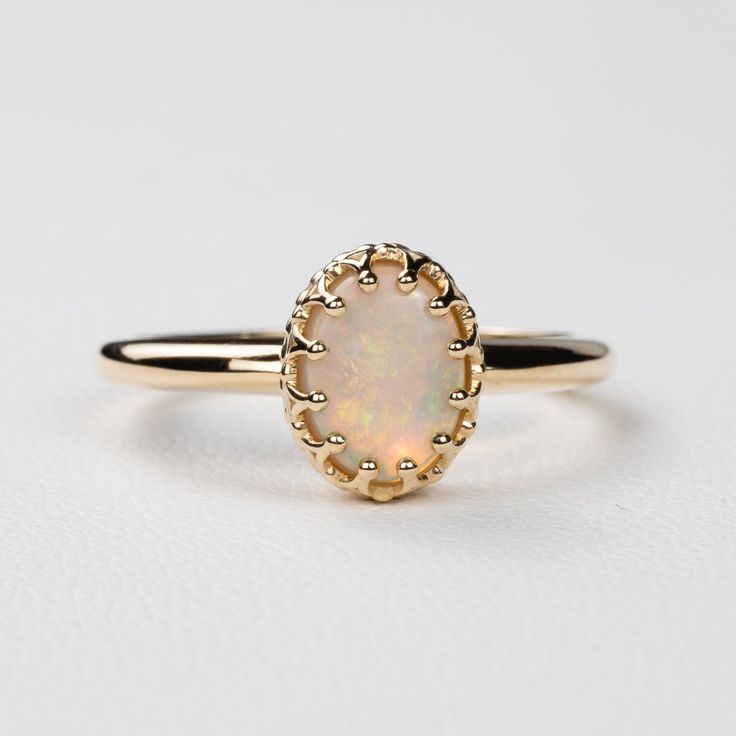 This antique style crown ring comes with a gorgeous Australian oval opal. If you want a different stone or want to add accent diamonds contact us for a quote. Details: - Default stone size is 7x5mm Australian Opal in oval shape. - Shiny finish by default. - Default width is 1.8mm at the bottom and 8.7x6.5mm at the top - Default thickness is 1.6mm at the bottom and 2mm at the top. - Contact us for quote if you want to customize this ring in any way. Thank you for shopping with Sevgi Jewelry! Classic 14k Gold Moonstone Ring Oval Cabochon, Heirloom 14k Gold Opal Ring With Halo, Exquisite Oval Opal Ring, Elegant Oval Cluster Ring With Cabochon, Elegant Oval Cabochon Cluster Ring, Heirloom Opal Ring Oval Cabochon, Classic Opal Gemstone Ring, 14k Gold Oval Cabochon Opal Ring For Anniversary, Heirloom 14k Gold Opal Ring Oval Cabochon