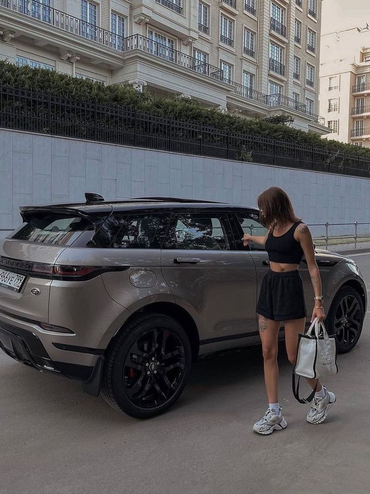 a woman standing next to a silver range rover