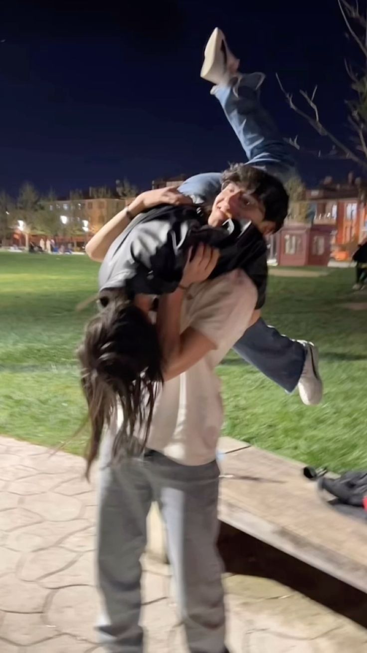 two people are doing tricks on a skateboard in the park at night with one person upside down