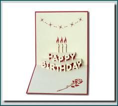 a happy birthday card with candles and flowers on the front, in red and white