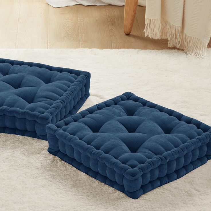 two blue cushions sitting on top of a white rug