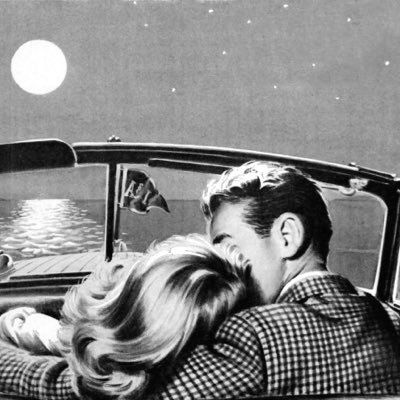 a man and woman are kissing in the back of a convertible car at night time