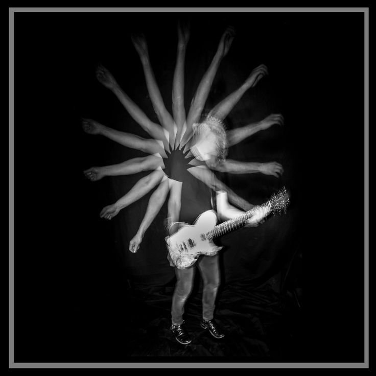 a man standing in front of a guitar while holding his hands out to the camera