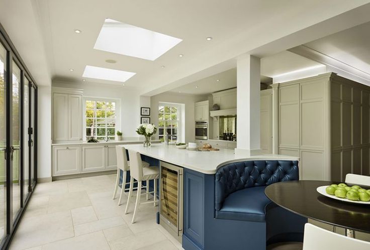 a large kitchen with an island and blue bench in the center, surrounded by white chairs