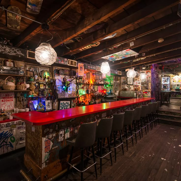 an empty bar with several stools and colorful lights on the wall in front of it