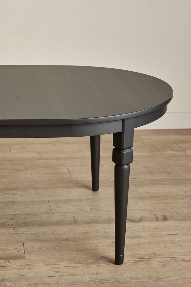 an oval table with black legs on a wooden floor