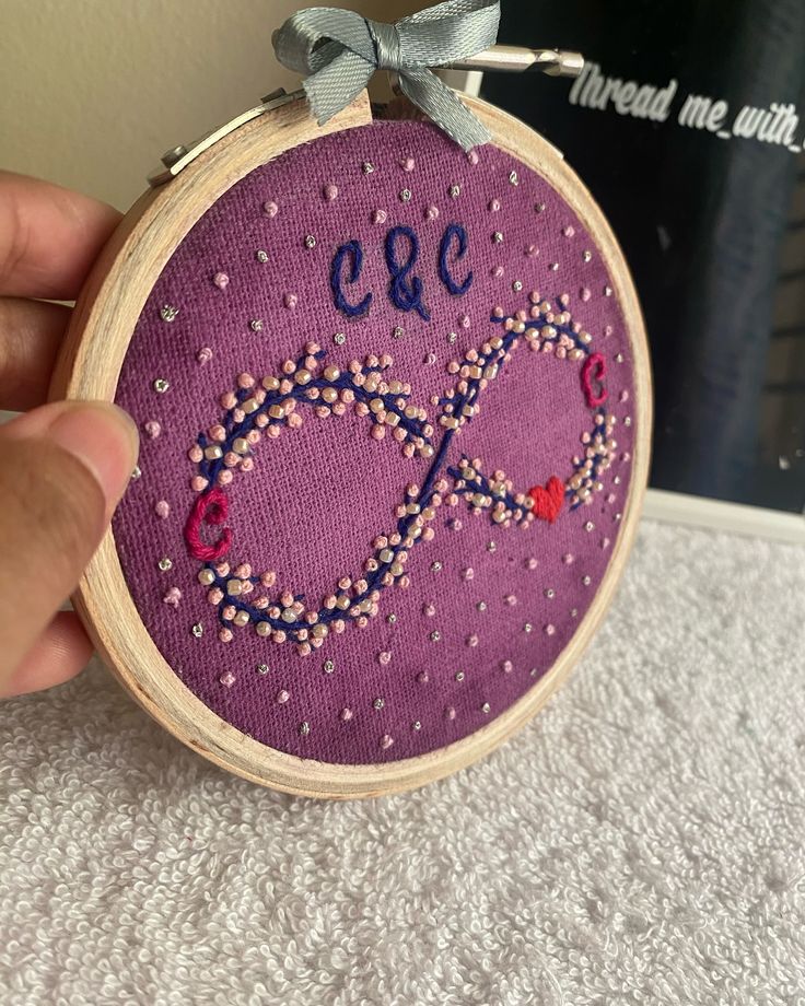 someone is holding up a small purple embroidered item with the word e & o on it