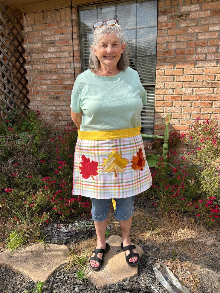 an older woman standing in front of a brick building with her hands on her hips