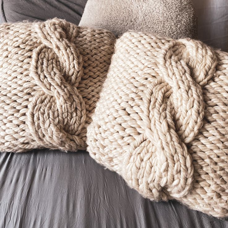 two knitted pillows sitting on top of a bed