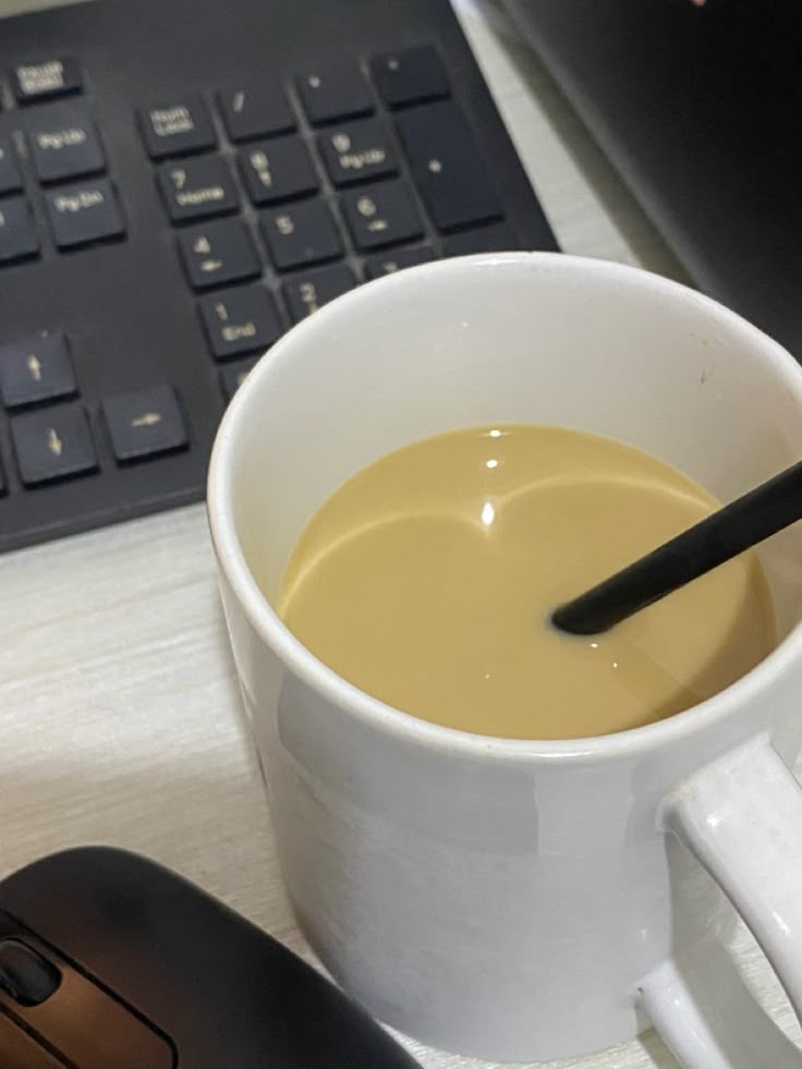 a cup of coffee next to a computer keyboard