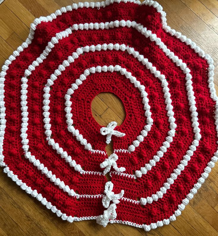 a red and white crocheted rug on top of a wooden floor