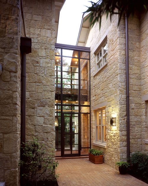 an entry way to a house with stone walls and glass doors that lead into the front yard