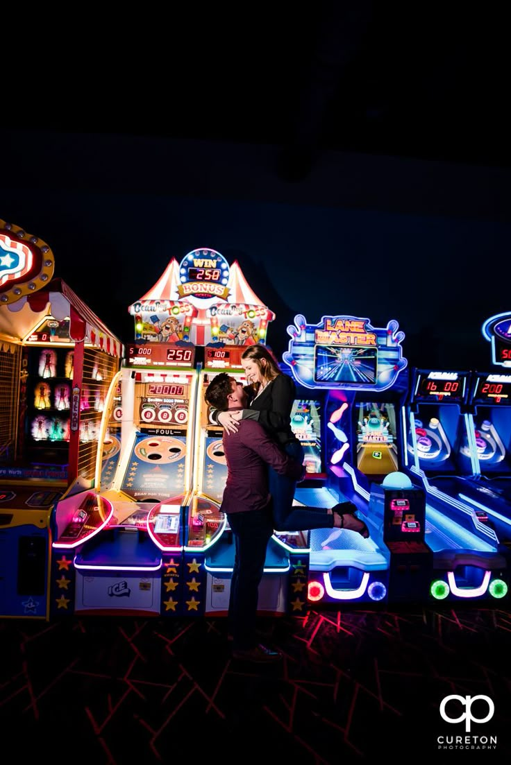 two people standing next to each other in front of an amusement park ride at night