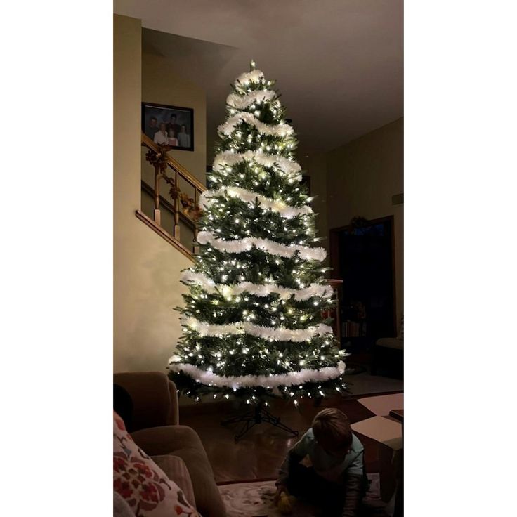 a white christmas tree is lit up in the living room