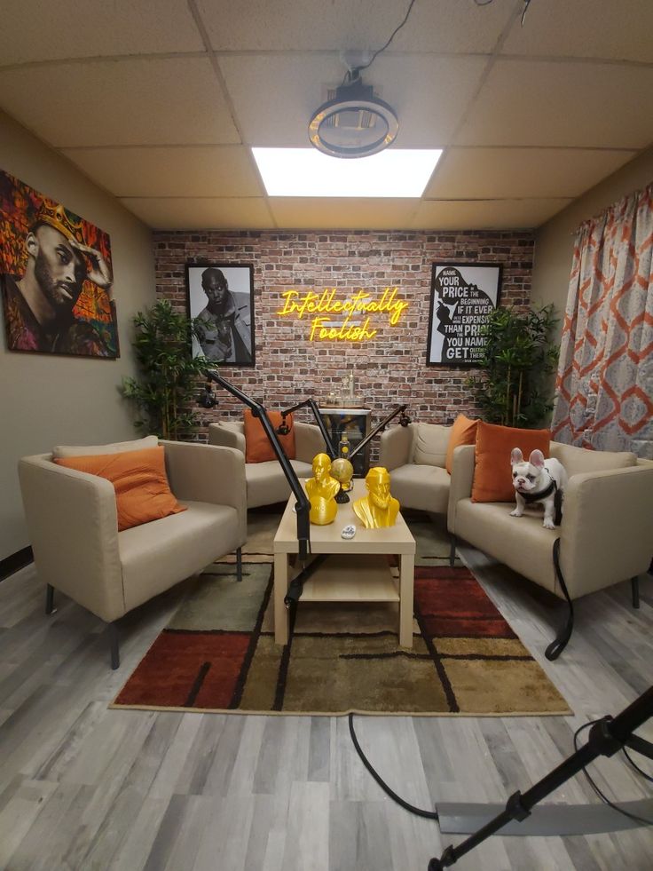 a living room with couches, chairs and pictures on the brick wall behind them