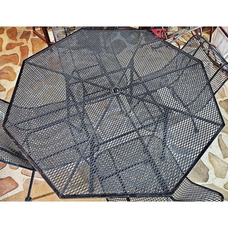 an outdoor table that is made out of metal mesh and has been placed on the ground