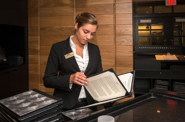 a woman standing in front of a counter holding an open book and looking at it