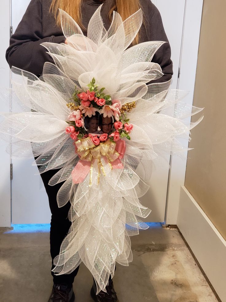 a woman is holding a wreath made out of tulle and plastic mesh with flowers on it