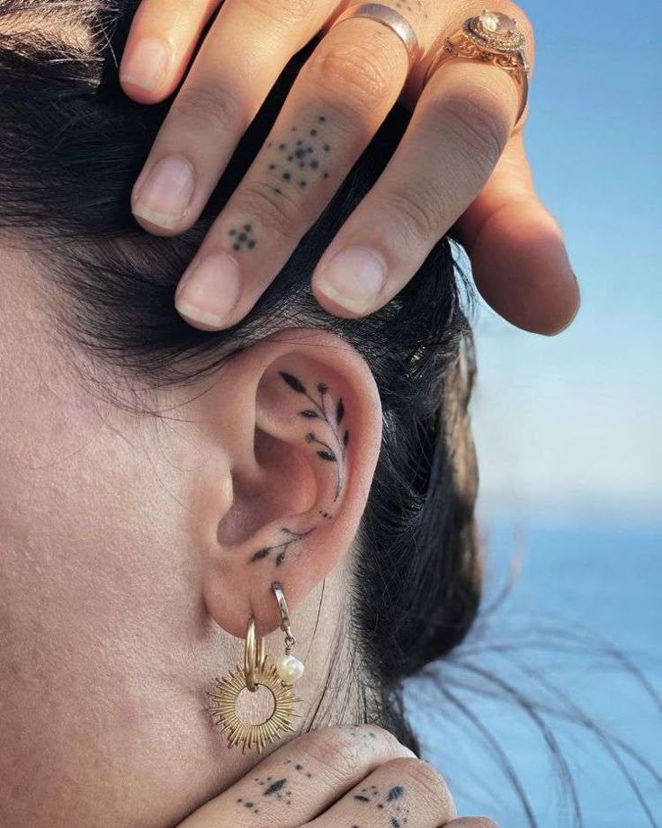 a close up of a person with tattoos on their ears and behind her ear is a ring