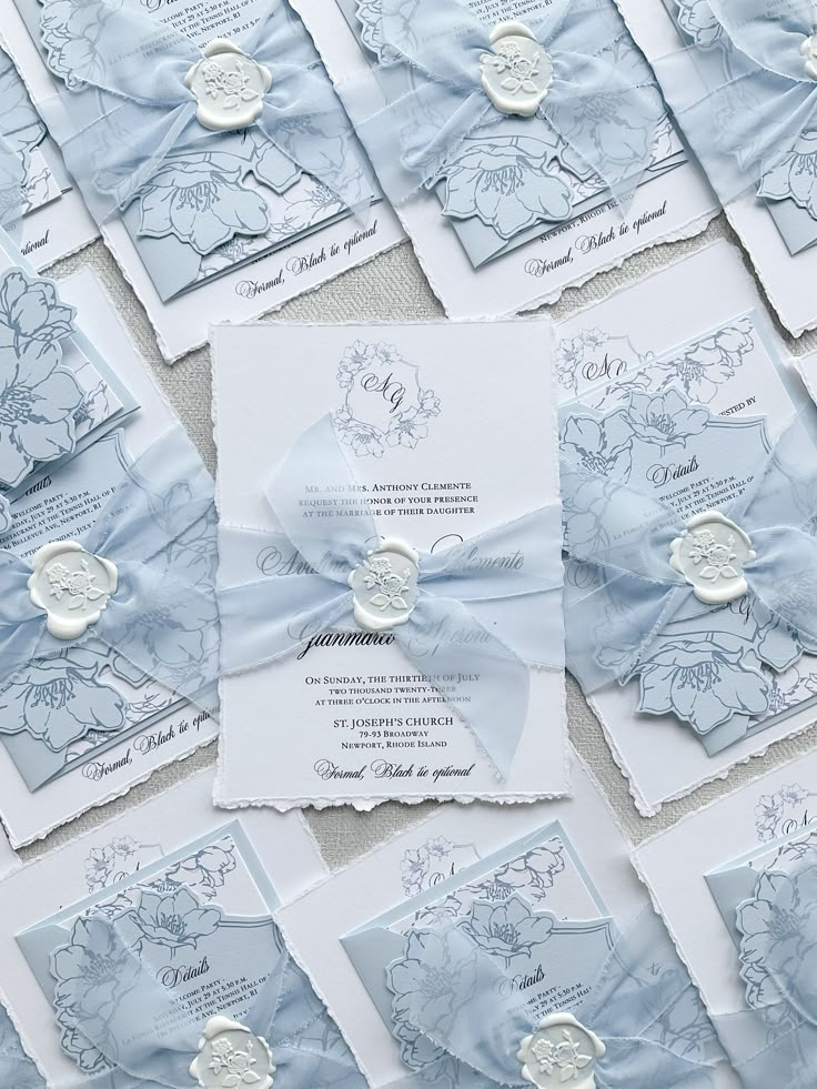 the wedding stationery is laid out on top of each other, with ribbons and buttons