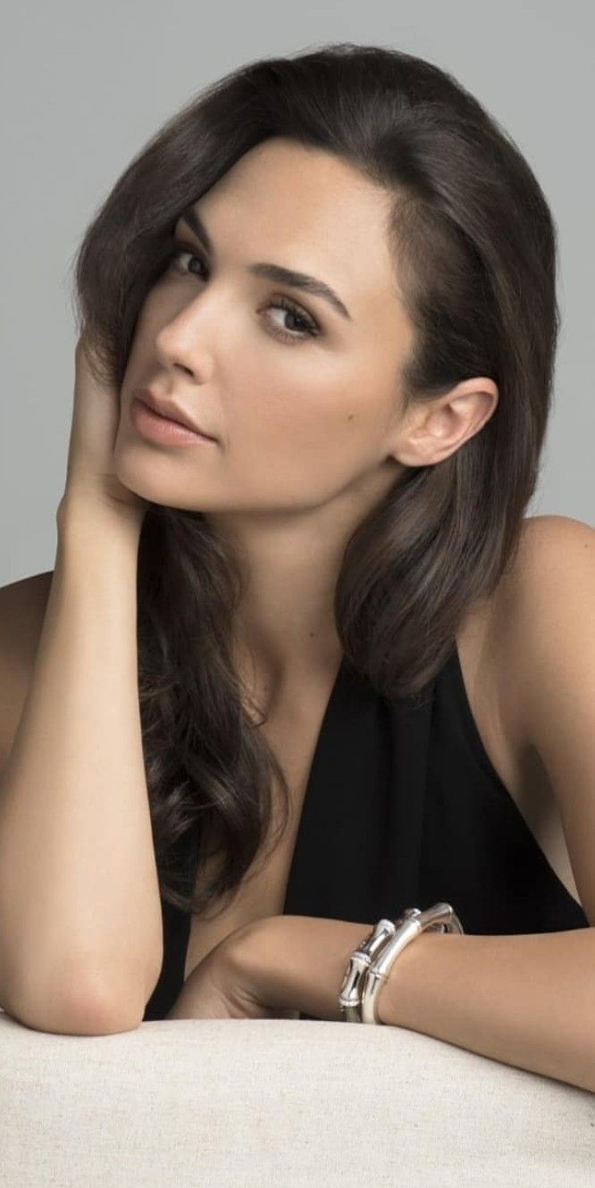 a woman sitting on top of a white couch with her hand on her chin and looking off to the side