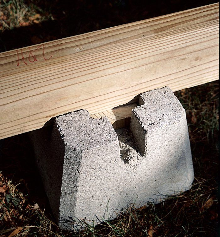 a piece of wood sitting on top of a cement block next to a wooden bench