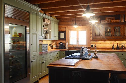 a kitchen with green cabinets and wood floors, along with an island in the middle