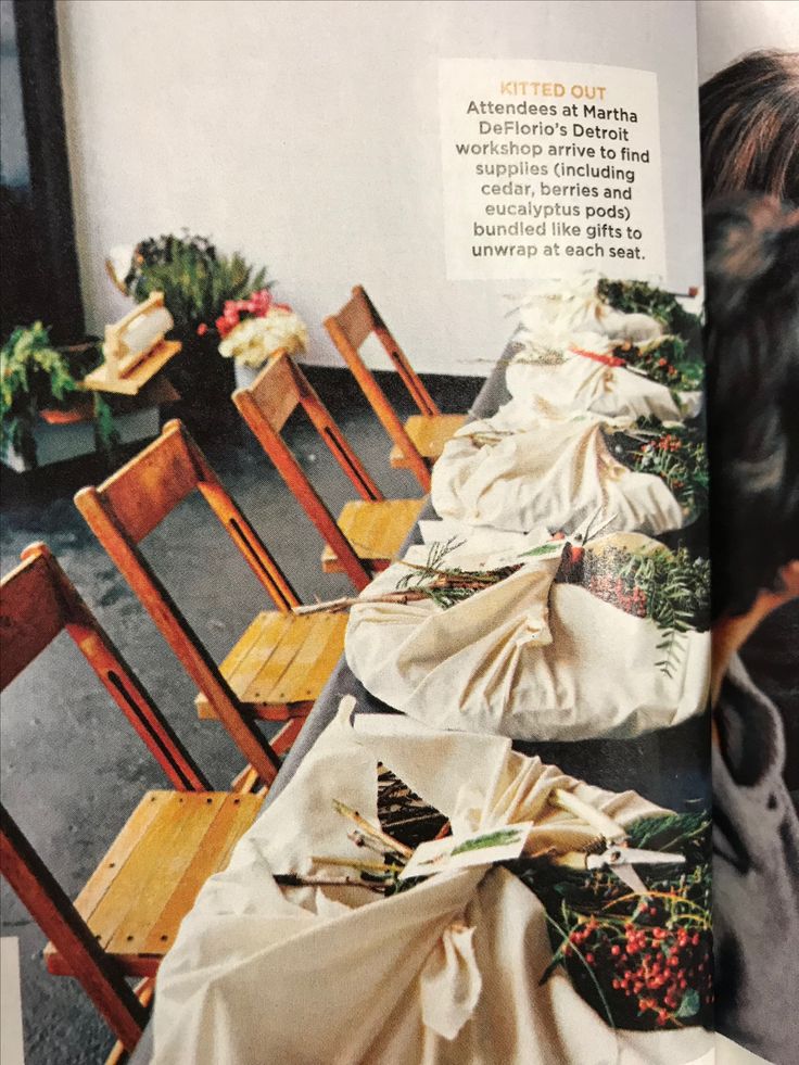 an open magazine with many wooden chairs covered in cloths and flowers on the table