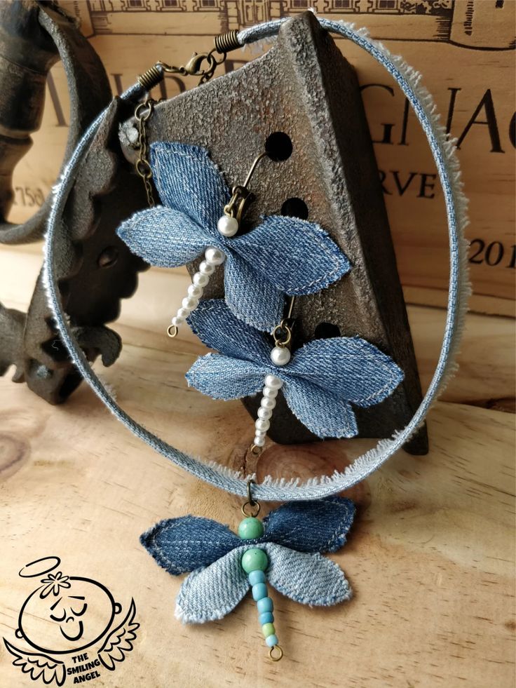 a necklace with blue flowers and beads hanging from it's side on a wooden table