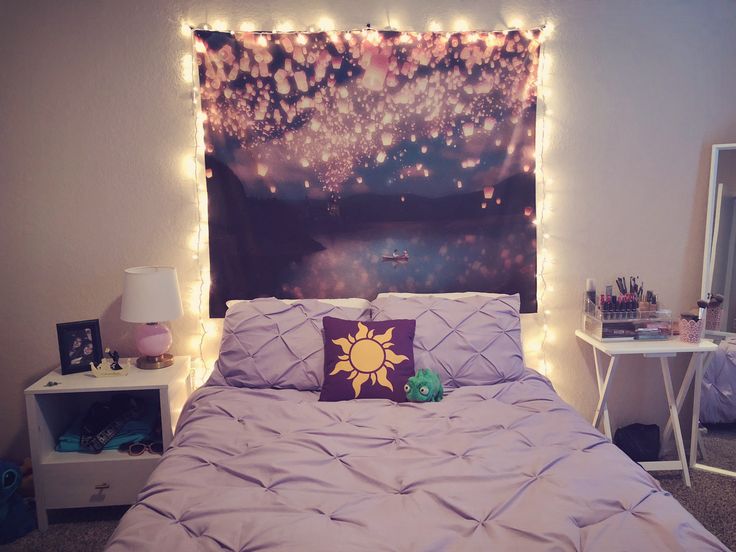 a bed with purple comforter and lights on the headboard, next to a night sky painting