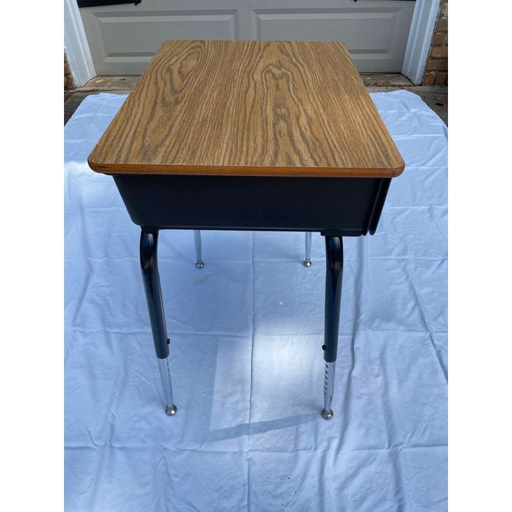 a small wooden table sitting on top of a white sheet covered floor next to a door