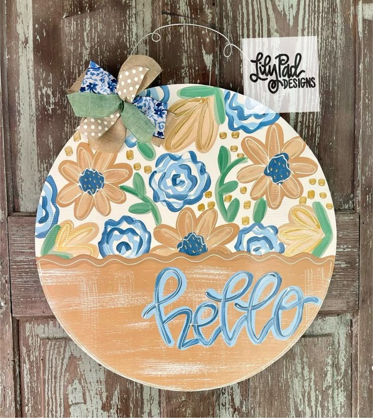 a painted wooden sign with flowers and the word hello written in blue ink on it