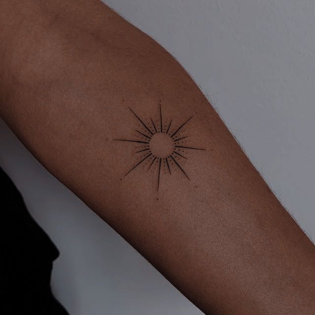 a woman's arm with a tattoo that has a sunburst on it