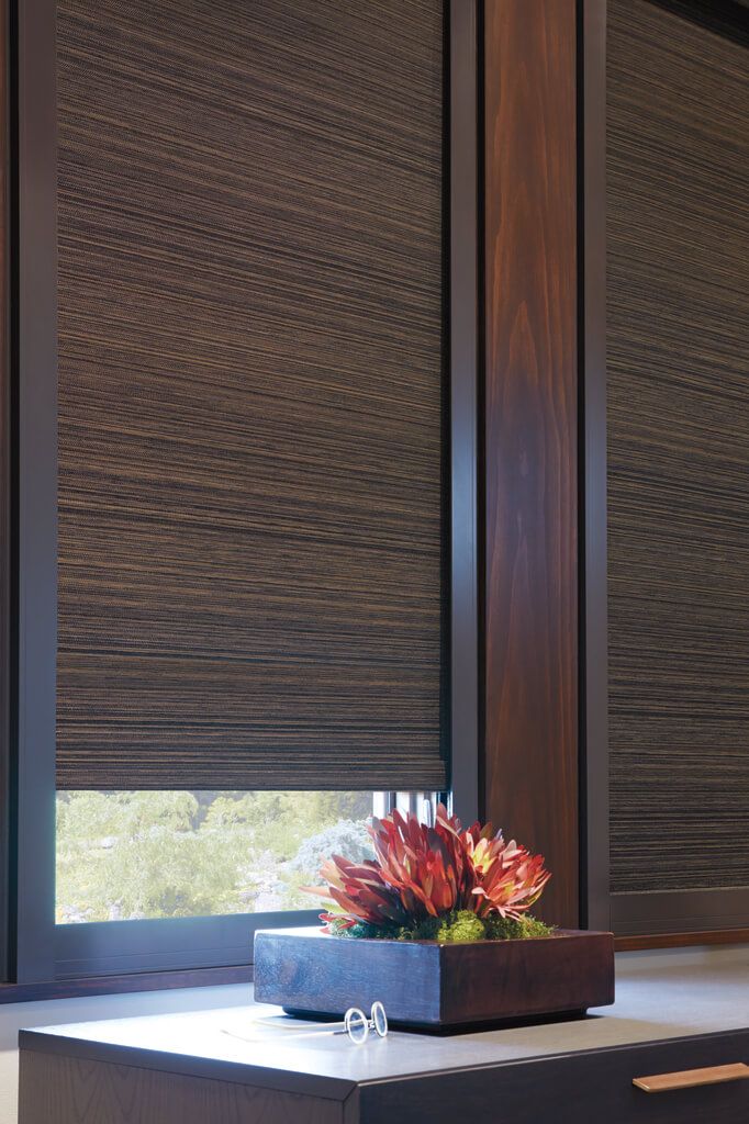 a vase with flowers on top of a table in front of some blinds that are closed