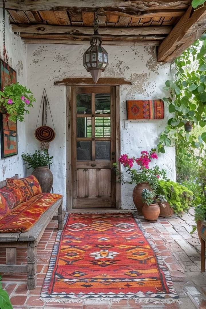 a room with a couch, rug and potted plants on the outside wall next to a wooden door