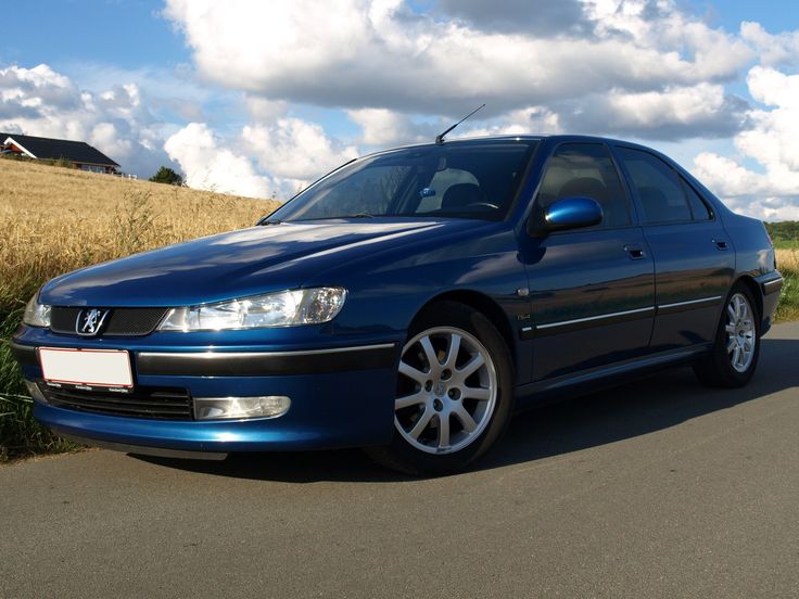 a blue car is parked on the side of the road in front of a field