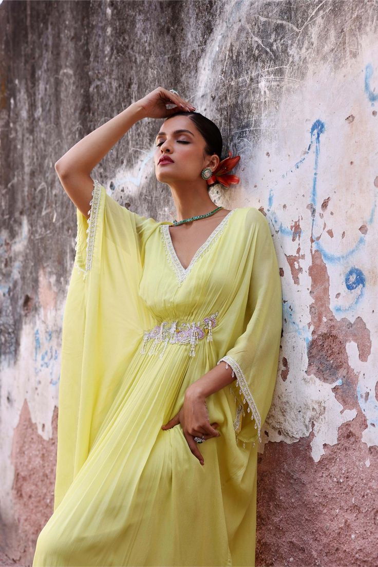 Step into effortless elegance with this full-length draped kaftan adorned with intricate embellishments. This kaftan offers a perfect balance of style and comfort, making it ideal for both casual outings and special occasions. Embrace luxury and grace with this stunning piece that's sure to turn heads wherever you go. Festive Green V-neck Kaftan, Green V-neck Kaftan For Festive Occasions, Embellished Summer Kurta With Traditional Drape, Bollywood Style Embellished Green Kaftan, Green Tunic Kaftan For Festive Occasions, Spring Designer Dress With Cape Sleeves, Designer Spring Dresses With Cape Sleeves, Festive Maxi Length Georgette Kaftan, Bohemian Georgette Dress With Cape Sleeves