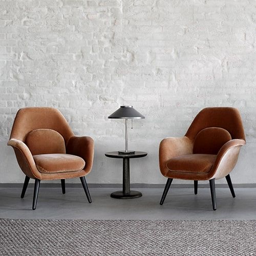 three chairs are lined up against a white brick wall, one has a lamp on it