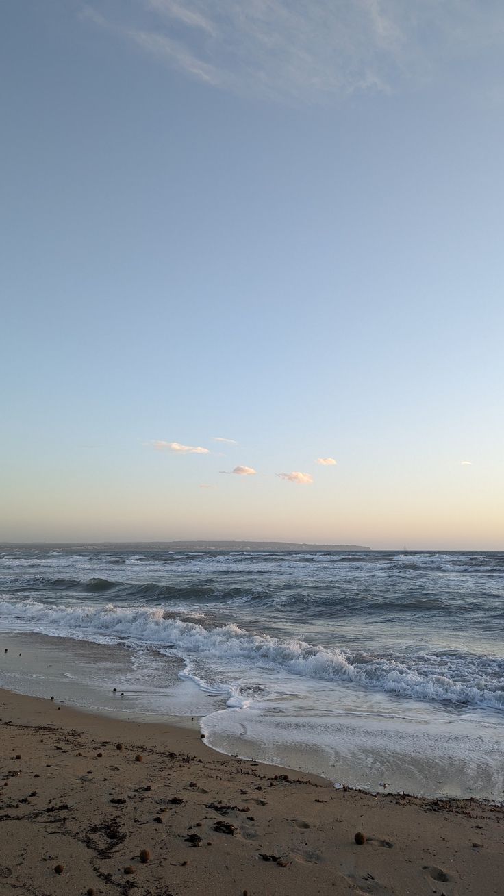 an empty beach with waves coming in to shore