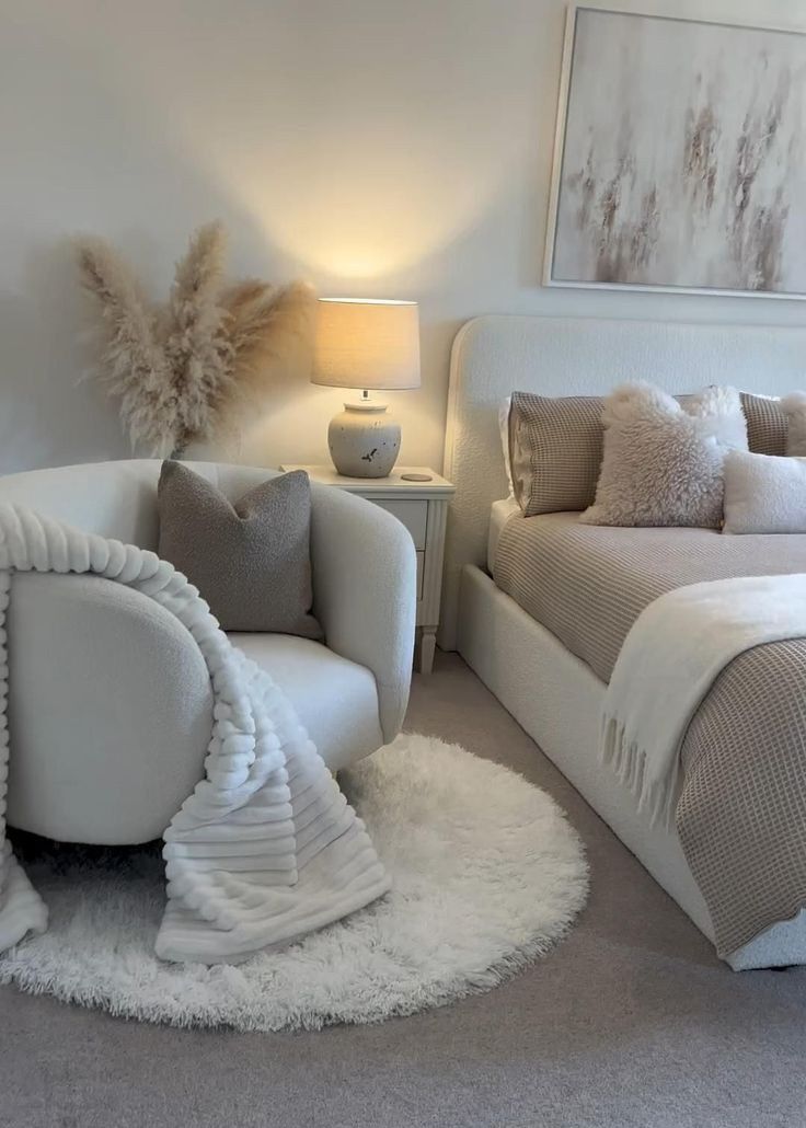 a white bed sitting next to a chair in a bedroom on top of a rug