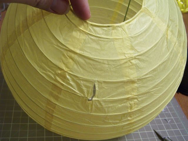 a person is making a paper lantern with scissors